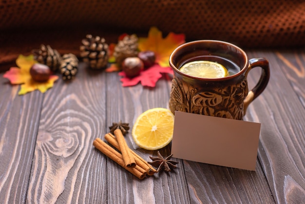 Een kopje thee met citroen en kaneelstokjes op een houten tafel warme gebreide snood herfststemming