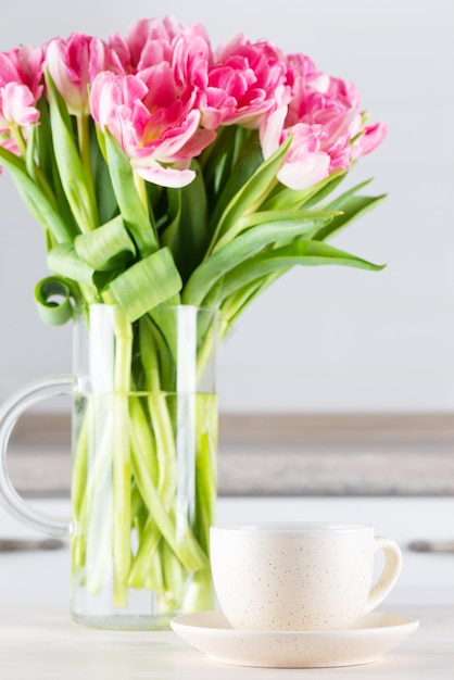 Een kopje thee met een boeket tulpen op tafel