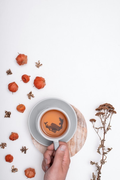 Een kopje thee op een witte achtergrond met herfstplanten plat lag kopieerruimte