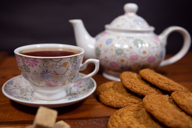 Een kopje verse hete thee met havermoutkoekjes op een donkere houten tafel