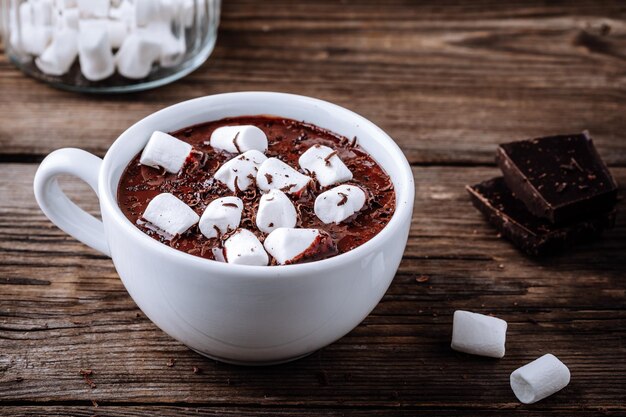 Een kopje warme chocolademelk of cacao met marshmallows op donkere houten achtergrond