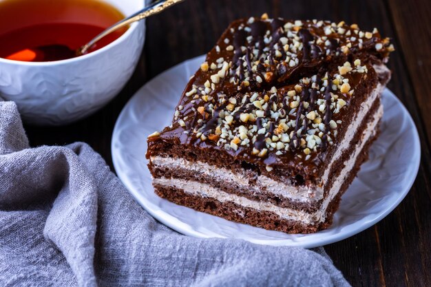 Een kopje zwarte thee en een bord met zelfgemaakte bakkerijkoekjes op een houten tafel