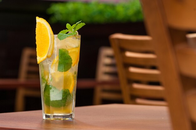 Een koud drankje met een gele citrus op tafel in een glas