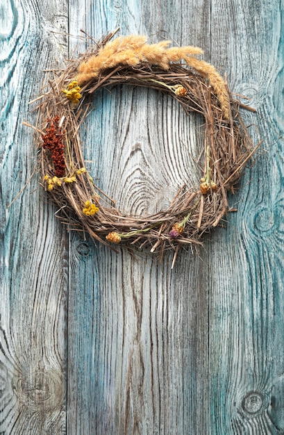 Een krans van gedroogde takken en wilde bloemen op een houten achtergrond