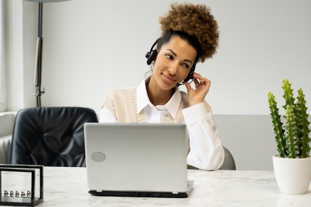 Een lachende Afro-Amerikaanse callcenteragent die een koptelefoon draagt met een microfoon die met een klant praat