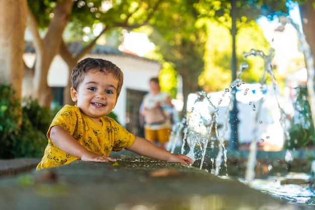 Een lachende baby die afkoelt van de hitte in de fontein in de gemeente Mijas in Malaga Andalusië