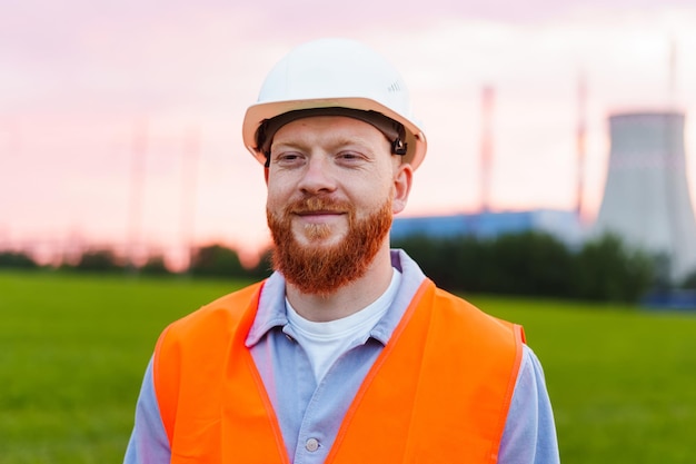 Een lachende ingenieur in een witte helm en een oranje vest