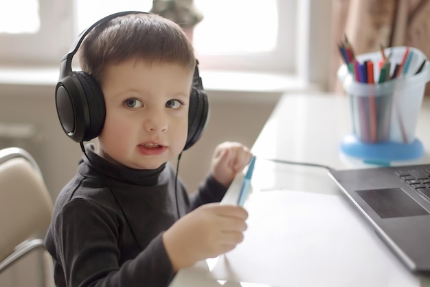 Een lachende jongen die thuis een koptelefoon draagt Homeschooling