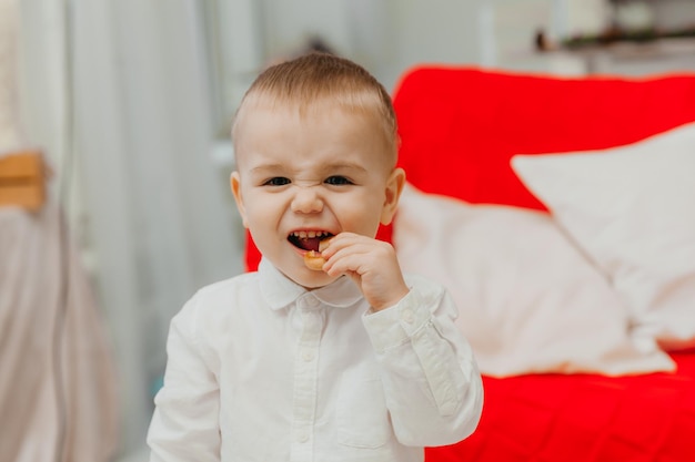 Een lachende jongen van 2 jaar staat op en eet een bagel.