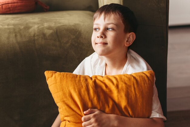 Een lachende jongen zit op de bank in de woonkamer. tiener rust thuis