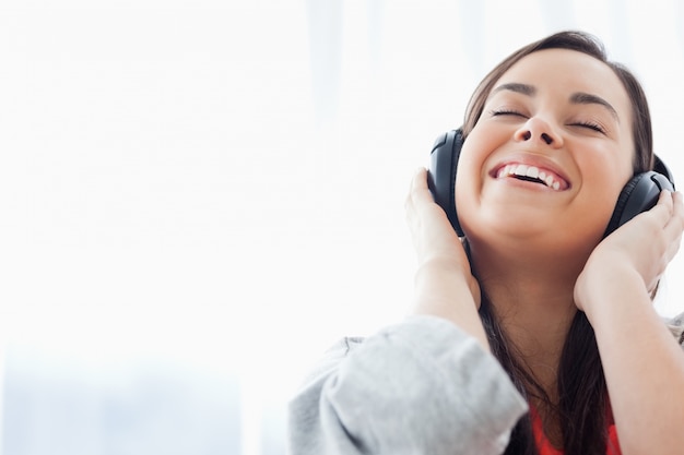 Een lachende vrouw die naar haar hoofdtelefoon luistert