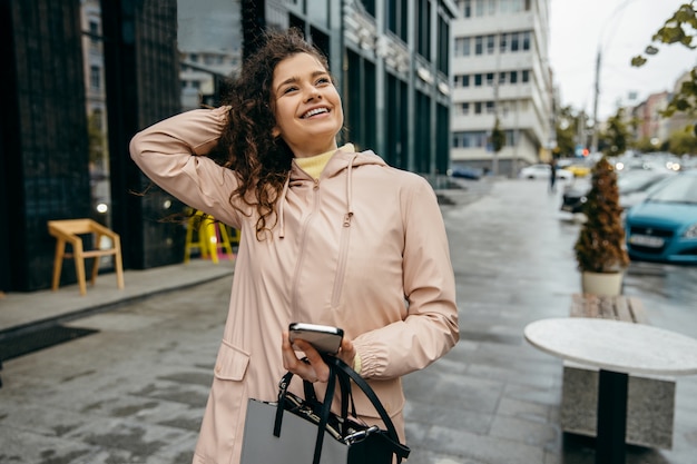 Een lachende vrouw met een roze jas op straat