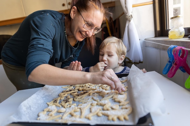 Een lachende vrouw met haar zoontje maakt koekjes in de keuken