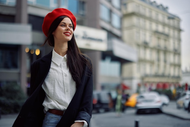 Een lachende vrouw met zakelijke tanden loopt door de stad tegen de achtergrond van kantoorgebouwen, stijlvolle modieuze kleding en make-up lentewandelingen