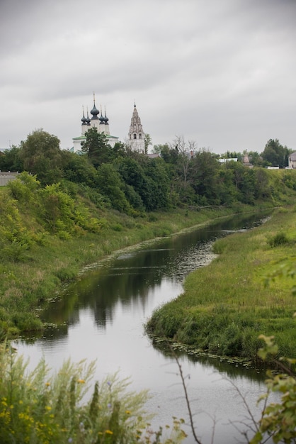 Een landschap van een klein dorp een kleine stroom grote kerk op een achtergrond Soezdal Rusland