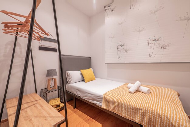 Een lange slaapkamer met een op maat gemaakte spiegel schuifdeurkast een wand bedekkend met een glanzende parketvloer en een houten bureau met een zwarte draaistoel