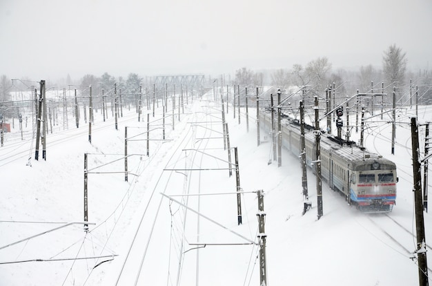 Een lange trein van personenauto&#39;s rijdt over het spoor. Spoorweglandschap in de winter na sneeuwval