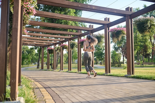 Een langharige vrouw in sportkleding die in het park jogt