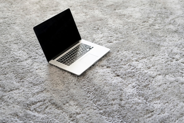 Een laptop en andere apparaten op de vloer op het zachte tapijt in de woonkamer thuis, isolatie tijdens coronavirus pandemie