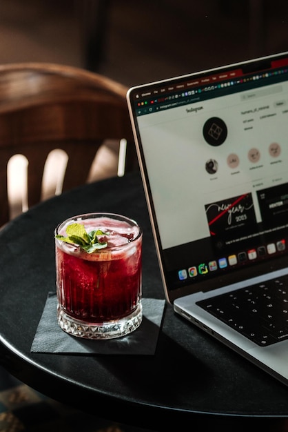 Foto een laptop en een glas cocktail staan op een tafel naast een laptop.