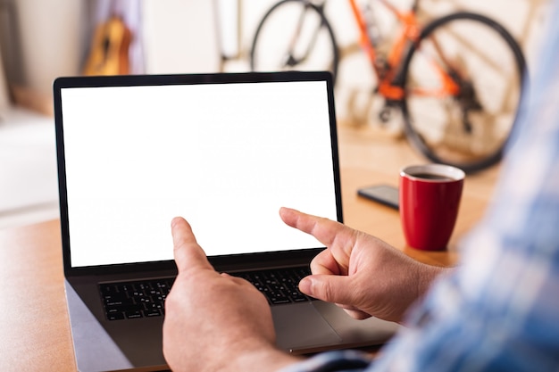 Een laptop met een leeg wit scherm op de achtergrond van een thuisomgeving.