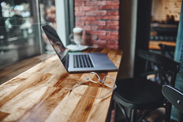 Foto een laptop om op afstand slim te werken bij het raam in een coffeeshop. gezellige werkplek