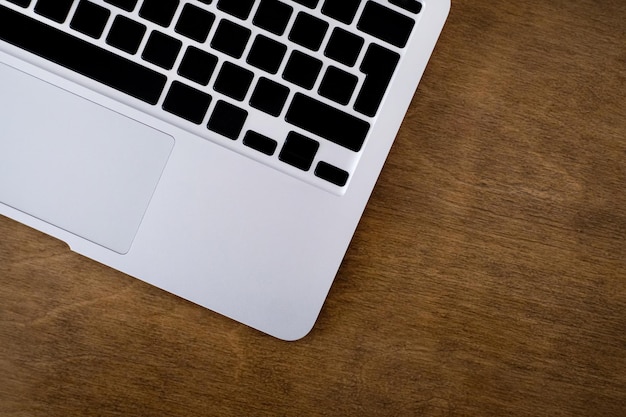 Een laptop toetsenbord op een houten achtergrond Wit zilver notebook op het bureaublad Bedrijfsconcept