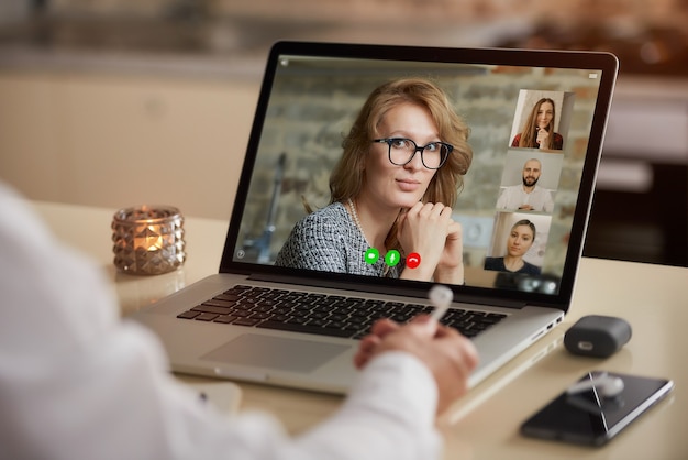 Een laptopweergave van de telecommunicatietoepassing tijdens een online vergadering over de schouder van een man.