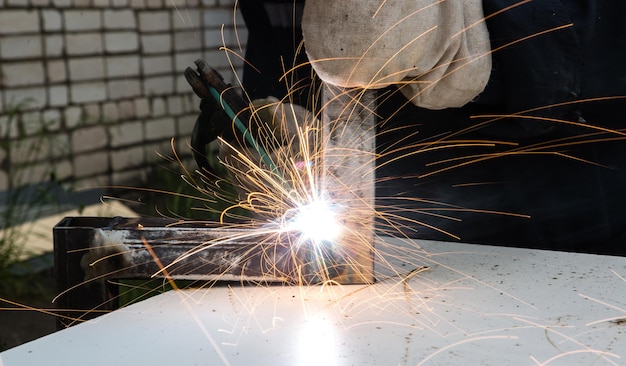 Een lasser last een metalen stuk en vonken van las vliegen in verschillende richtingen