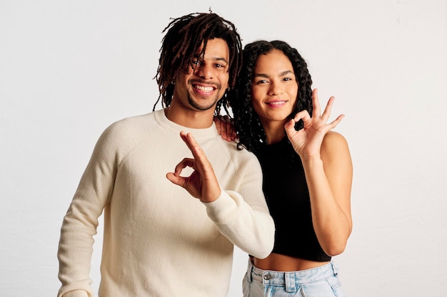 Foto een latijns stel dat het ok-symbool maakt met hun handen kijkend naar de camera in een studio-opname