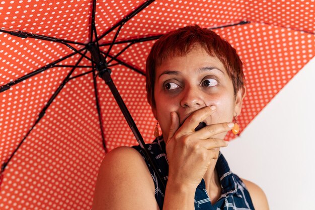 Een Latijnse vrouw van middelbare leeftijd houdt een paraplu vast en toont verbazing