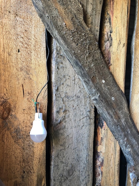 Een led-lamp op zonne-energie hangt aan een muur van onbehandelde houten planken