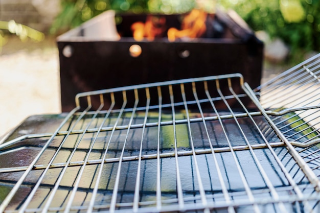 Een leeg grillrooster op de achtergrond van een barbecue die is voorbereid voor het voeren van vlees of groenten erop. rust in de natuur.