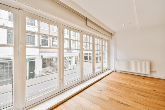 Foto een lege kamer met houten vloer en grote ramen met uitzicht op de straat voor het appartementengebouw