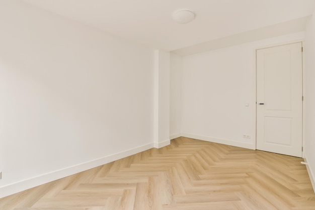 een lege kamer met witte muren en een geparkeerde houten vloer in het midden van de kamer is erg schoon