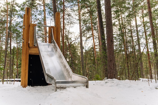 Een lege kinderglijbaan in een winterpretpark tussen de pijnbomen