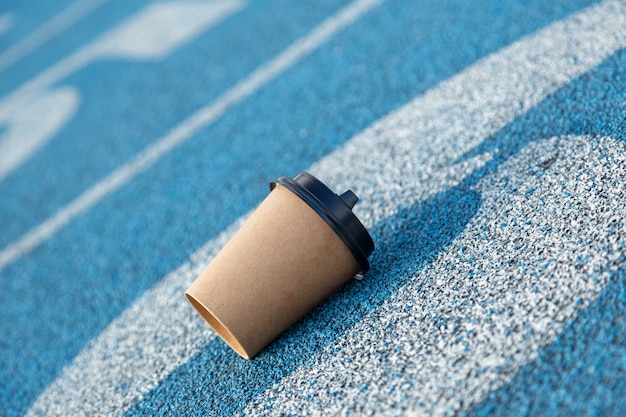 Een lege koffiekop op de startlijn van de atletiekbaan