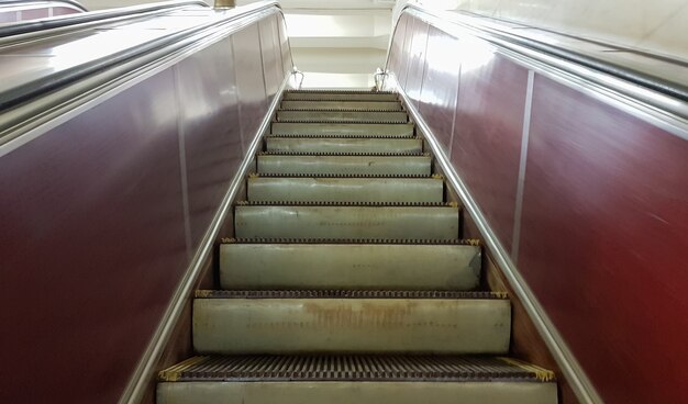 Een lege roltrap zonder mensen bij het metrostation op de rode lijn van de metro van Kiev. Close up van metalen treden van een roltrap die van onder naar boven beweegt.