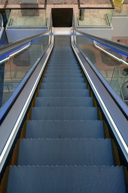 Een lege roltraptrap in een modern winkelcentrum leidt naar beneden. Het concept van klanten die van winkelcentra naar internet verhuizen.