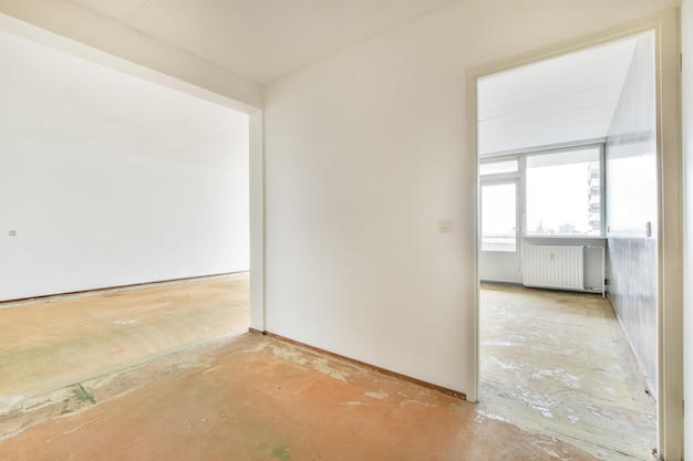 Een lege ruime kamer met grote ramen en witte muren in een appartement van een woongebouw