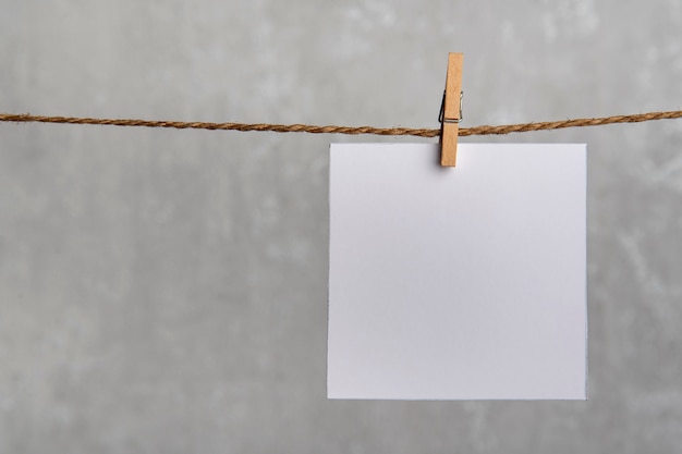 Een lege vierkante notitie papier kaart opknoping met houten clip op touw koord pin