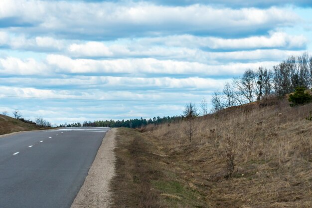 Een lege weg buiten de stad passeert een landelijk veld en een bloeiende weide Reis met de auto weg van de stad en de drukte Verharde weg op een zonnige dag zonder auto's