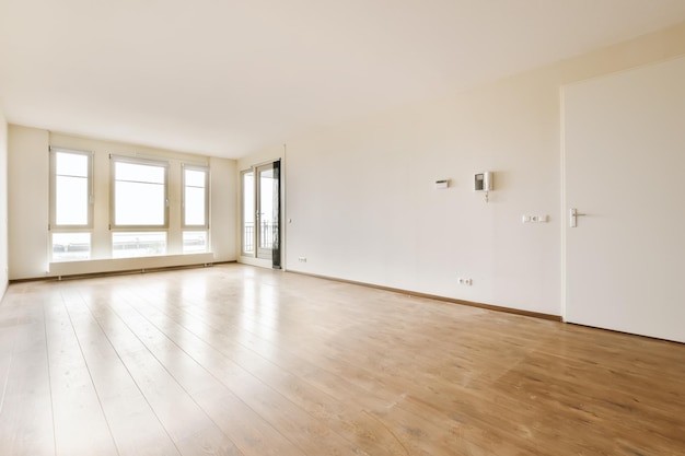 Foto een lege woonkamer met houten vloeren en grote ramen in de kamer is erg schoon, maar het is helemaal wit