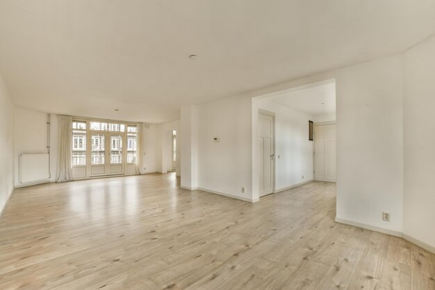 Een lege woonkamer met witte muren en houten vloeren