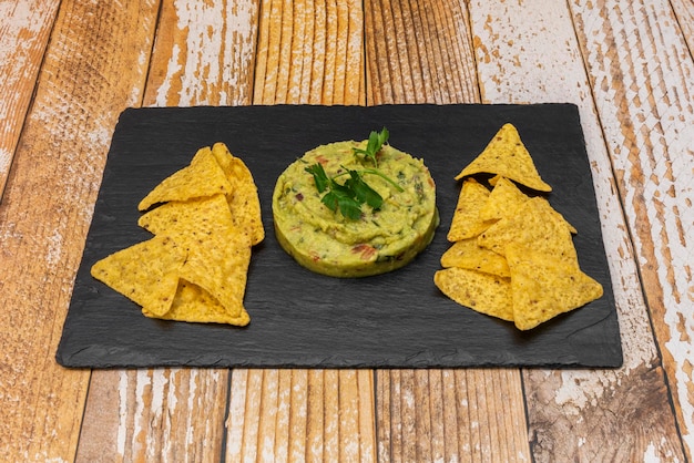 Een leistenen dienblad met als voorgerecht Mexicaanse guacamole met maïstortillachips