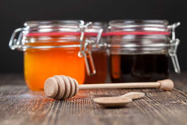 Een lepel voor honing samen met hoogwaardige bijenhoning, een oude tafel waarop een gezonde en zoete bijenhoning staat en een houten speciale lepel
