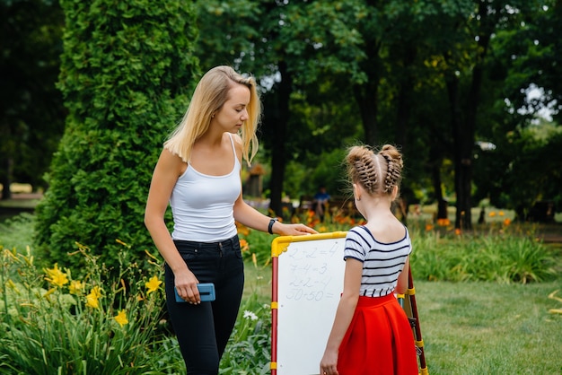 Een leraar geeft les aan een klas kinderen in een openluchtpark. Terug naar school, leren tijdens de pandemie.