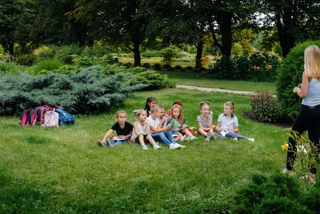 Een leraar geeft les aan een klas kinderen in een openluchtpark. Terug naar school, leren tijdens de pandemie.