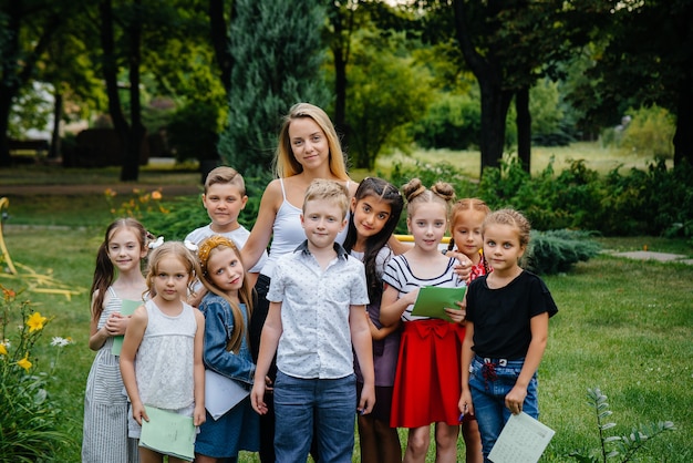 Een leraar geeft les aan een klas kinderen in een openluchtpark. terug naar school, leren tijdens de pandemie.