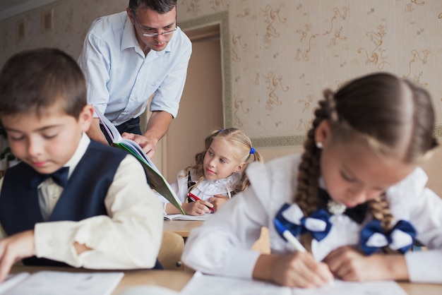 Een leraar op school leert kinderen zorgvuldig een boek voor te lezen